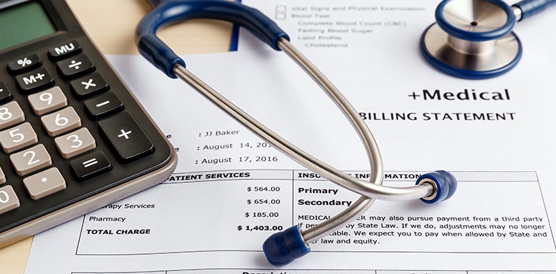 Stethoscope on top of medical bill papers with calculator