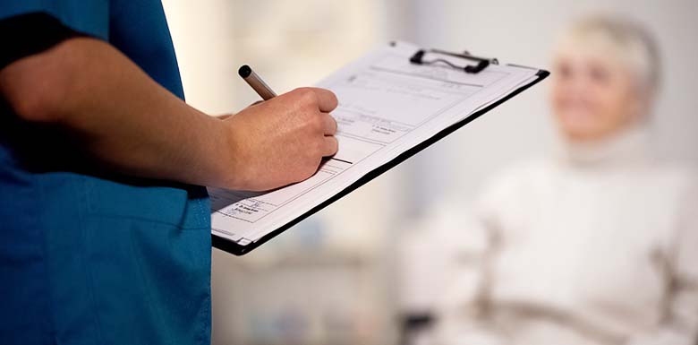 Medical professional filling in clipboard document