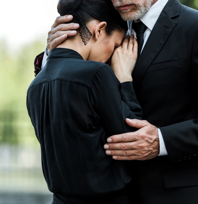 Couple crying at funeral dressed in black