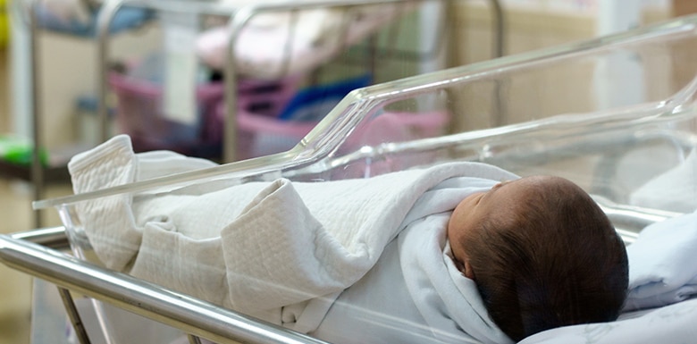 Newborn baby in hospital room wrapped in blanket
